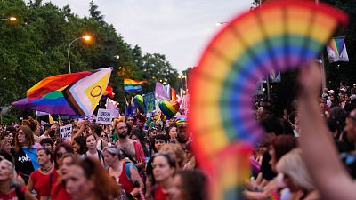 Marcha del Orgullo LGTBIQ+ en Madrid al anochecer, con multitud, Bandera de Progreso y carteles reivindicativos. Ambiente festivo y de celebración. Marcha del Orgullo LGTBIQ+ en Madrid al anochecer, con multitud, Bandera de Progreso y carteles reivindicativos. Ambiente festivo y de celebración.
