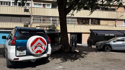 Vehicle policial dels Mossos d'Esquadra davant d'un edifici amb un bar. Es veuen persones a la vorera i als balcons. Vehicle policial dels Mossos d'Esquadra davant d'un edifici amb un bar. Es veuen persones a la vorera i als balcons.