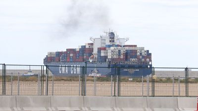 El vaixell portacontenidors "CMA CGM PELLEAS" (VALLETTA) navega amb l'ajuda de remolcadors, carregat de contenidors i amb fum sortint de la xemeneia, sota un cel ennuvolat. El vaixell portacontenidors "CMA CGM PELLEAS" (VALLETTA) navega amb l'ajuda de remolcadors, carregat de contenidors i amb fum sortint de la xemeneia, sota un cel ennuvolat.