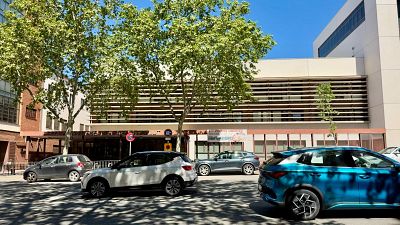 Una vista de la Gran Via de Sabadell amb cotxes en moviment davant d'un edifici modern, possiblement un centre educatiu, amb arbres i senyals de trànsit. Una vista de la Gran Via de Sabadell amb cotxes en moviment davant d'un edifici modern, possiblement un centre educatiu, amb arbres i senyals de trànsit.