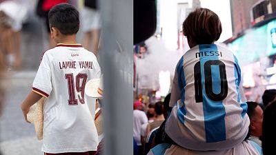 Dos jóvenes aficionados, uno con la camiseta de Lamine Yamal (España) y otro con la de Messi (Argentina), disfrutan del ambiente del fútbol. Dos jóvenes aficionados, uno con la camiseta de Lamine Yamal (España) y otro con la de Messi (Argentina), disfrutan del ambiente del fútbol.
