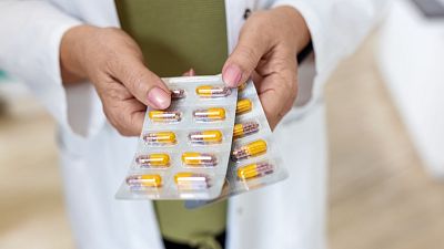 Imagen de un médico sosteniendo antibióticos en una consulta para ilustrar la bajada del consumo en España.