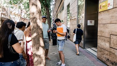 Varias personas migrantes esperan en el exterior de una oficina de la Seguridad Social