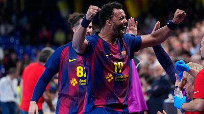 Djylian N'Guessan del Barça celebra con euforia, puños en alto y boca abierta, luciendo el número 79 en su camiseta azulgrana con el patrocinador Assistència Sanitària. Fondo de pabellón deportivo.