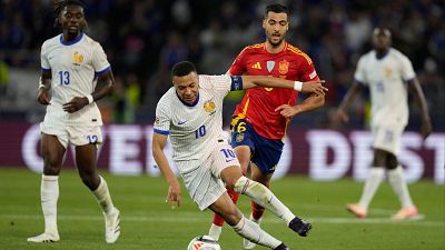 Partido de fútbol España-Francia: jugador francés (dorsal 10) con el balón, a punto de regatear a un rival español.  Se ven otros jugadores al fondo.