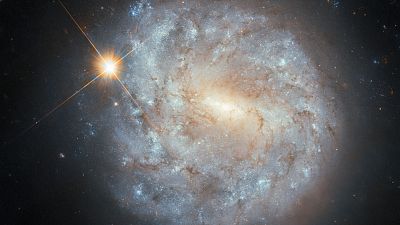 El Hubble capta una galaxia lejana y una estrella cercana con datos tomados con 20 años de diferencia