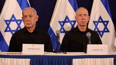 Netanyahu y Gallant, en una mesa con micrófonos, frente a carteles y con tres banderas israelíes de fondo. Netanyahu y Gallant, en una mesa con micrófonos, frente a carteles y con tres banderas israelíes de fondo.