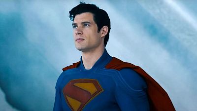 Superman, en su clásico traje, con mirada seria hacia arriba, sobre un fondo de cielo azul con nubes. Superman, en su clásico traje, con mirada seria hacia arriba, sobre un fondo de cielo azul con nubes.
