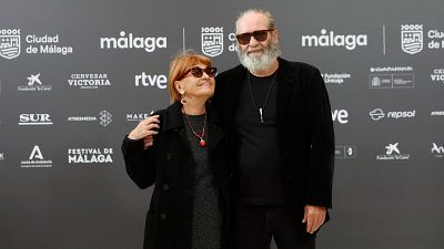 Jorge Perugorría y Mirtha Ibarra, ambos con gafas de sol, posan frente a un panel gris con logotipos. Mirtha Ibarra luce un abrigo negro y un collar rojo, mientras que Jorge Perugorría lleva una camiseta y chaqueta negras. Jorge Perugorría y Mirtha Ibarra, ambos con gafas de sol, posan frente a un panel gris con logotipos. Mirtha Ibarra luce un abrigo negro y un collar rojo, mientras que Jorge Perugorría lleva una camiseta y chaqueta negras.