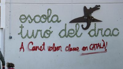 Fachada de l'escola Turó del Drac amb pintada "A Canet volem classe en CATALÀ!" en vermell, nom de l'escola en verd i logotip de drac. Fachada de l'escola Turó del Drac amb pintada "A Canet volem classe en CATALÀ!" en vermell, nom de l'escola en verd i logotip de drac.