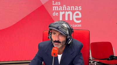 Leiva, con gorra de cuadros y auriculares, está en un estudio de radio frente a un micrófono naranja con el logo de RNE, con el fondo rojo y el logo de "Las mañanas de RNE".