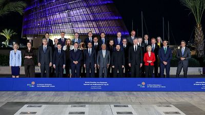 Líderes de la UE y Volodímir Zelenski en una cumbre informal en Chipre, frente a un edificio iluminado y palmeras. Se distingue un cartel con "CY23.EU" y "23 April Ayia Napa, Cyprus".