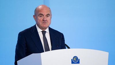 Luis de Guindos, Vicepresidente del BCE, en un podio blanco con el logo de la institución. Viste traje azul marino y corbata oscura. Luis de Guindos, Vicepresidente del BCE, en un podio blanco con el logo de la institución. Viste traje azul marino y corbata oscura.