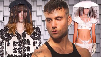 Diseñador de moda con dos modelos mostrando diseños contrastantes: chaqueta torera bordada y conjunto de lencería blanca con tocados. Fondo geométrico.