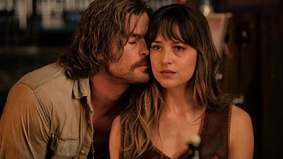 Chris Hemsworth y Dakota Johnson comparten un momento íntimo y emotivo, con Hemsworth susurrando o consolando a Johnson, quien muestra una expresión seria y una marca en el rostro. Chris Hemsworth y Dakota Johnson comparten un momento íntimo y emotivo, con Hemsworth susurrando o consolando a Johnson, quien muestra una expresión seria y una marca en el rostro.