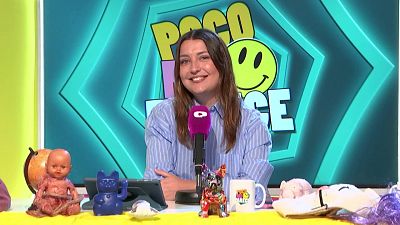 Inés Hernand sonríe a cámara en un set de televisión con el logo "POCO ME PARECE" y un emoji sonriente de fondo. Sobre su escritorio amarillo, un micrófono magenta y diversos objetos decoran la escena.