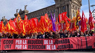 Multitud manifestándose en Barcelona por la reducción de la jornada laboral. Pancartas de CCOO y UGT reclaman jornadas más cortas. Numerosas banderas sindicales presentes. Multitud manifestándose en Barcelona por la reducción de la jornada laboral. Pancartas de CCOO y UGT reclaman jornadas más cortas. Numerosas banderas sindicales presentes.