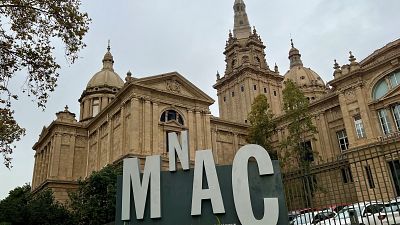 El Museu Nacional d'Art de Catalunya (MNAC) a Barcelona, amb el seu nom en grans lletres blanques davant de l'edifici monumental sota un cel ennuvolat. El Museu Nacional d'Art de Catalunya (MNAC) a Barcelona, amb el seu nom en grans lletres blanques davant de l'edifici monumental sota un cel ennuvolat.