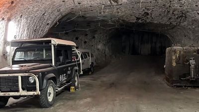 Interior de mina con vehículo utilitario "TK PREV 605" y maquinaria industrial. Túnel rocoso con iluminación tenue. Interior de mina con vehículo utilitario "TK PREV 605" y maquinaria industrial. Túnel rocoso con iluminación tenue.