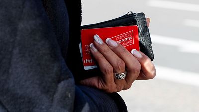 Mano femenina con manicura francesa, cartera negra y tarjeta roja del Consorcio Transportes Madrid. Anillo plateado en dedo anular.