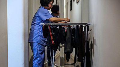 Una treballadora de la llar penjant roba a l'estenedor