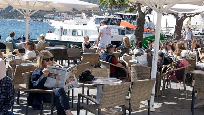 Terrasses plenes i, al fons, una embarcació a Cadaqués