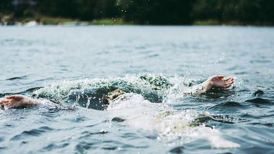 Imagen de una persona aparentemente ahogándose en el mar; cuerpo boca abajo, brazos extendidos. El agua es oscura y tranquila, con pequeñas ondas. Imagen de una persona aparentemente ahogándose en el mar; cuerpo boca abajo, brazos extendidos. El agua es oscura y tranquila, con pequeñas ondas.