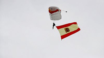 El paracaidista que descendía con la bandera de España impacta contra una farola y queda enredado