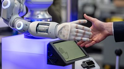 Un robot y un ser humano estrechan sus manos en un gesto de saludo y acuerdo