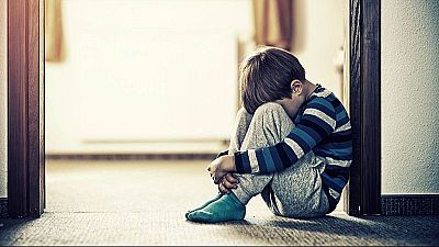 Un menor ajupit a terra a casa seva