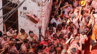 Multitud eufórica y cubierta de tomate en la Tomatina de Buñol, con participantes usando gafas protectoras y celebrando en una calle teñida de rojo. Multitud eufórica y cubierta de tomate en la Tomatina de Buñol, con participantes usando gafas protectoras y celebrando en una calle teñida de rojo.