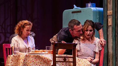 Nathalie Poza, Pablo Derqui y María Vázquez interpretan una escena con tensión en un ambiente evocador de época pasada, con una mesa, comida y una nevera antigua. Nathalie Poza, Pablo Derqui y María Vázquez interpretan una escena con tensión en un ambiente evocador de época pasada, con una mesa, comida y una nevera antigua.