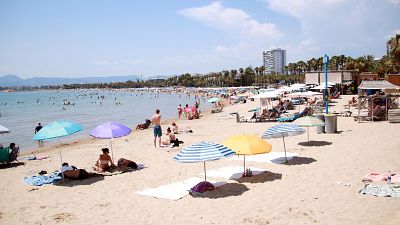 Turistes i banyistes prenent el sol i banyant-se a la platja de Salou