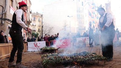 Dos homes retiren de les brases calçots per ser cuits a la Gran Festa de la Calçotada de Valls