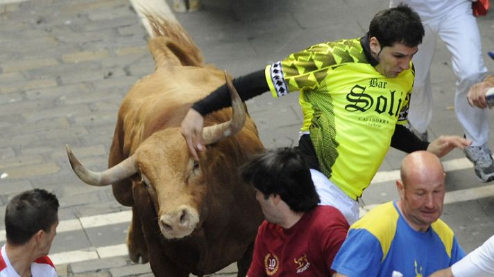 San Fermín - El animal rojizo casi cornea el brazo a un mozo de verde