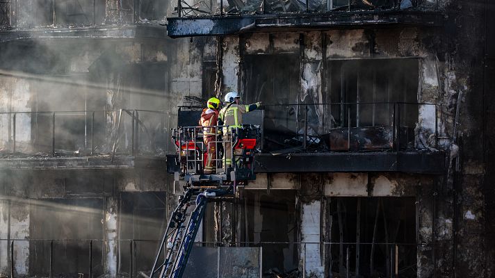 Los bomberos inspeccionan la fachada principal de los edificios incendiados