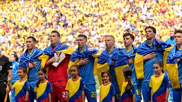 Los jugadores de Ucrania entonan el himno de su pas envueltos en su bandera