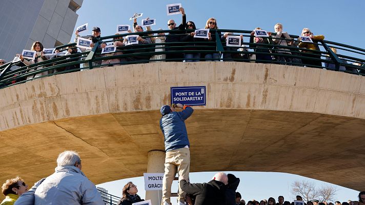 Acto público en un puente, personas colocando carteles con mensajes de agradecimiento.  Se observa participación comunitaria.