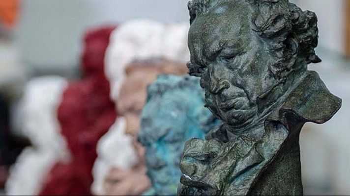 Primer plano de un busto de bronce oscuro, posiblemente de Beethoven, con otros bustos borrosos al fondo.  Ambiente de taller o exposición.