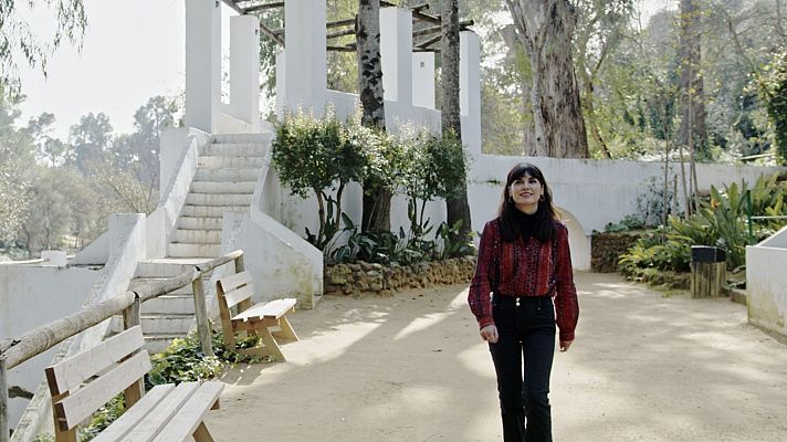 Mujer en parque con arquitectura blanca, promocionando \"Un País Para Leer 92 Preview\".  Ambiente tranquilo y acogedor.