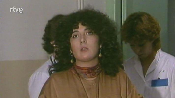 Minuto de silencio en TVE Miramar. Presentadora con cabello oscuro y blusa marrón, rodeada de personas con expresiones serias.