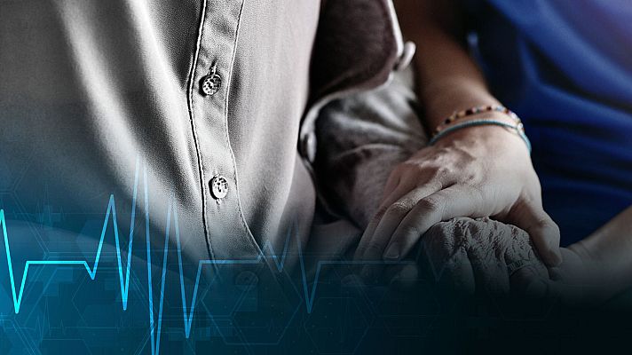 Manos entrelazadas: una envejecida y otra joven, sobre un fondo en escala de grises con una línea azul de electrocardiograma superpuesta. Simboliza la conexión humana y la fragilidad de la vida.
