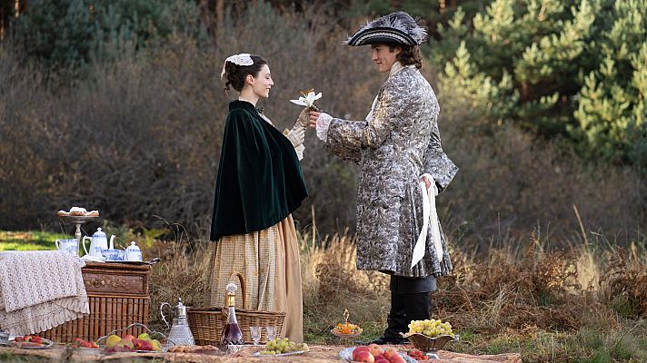 Picnic romántico al aire libre: pareja de época, comida, flores y detalles como una cesta y mesa de mimbre.