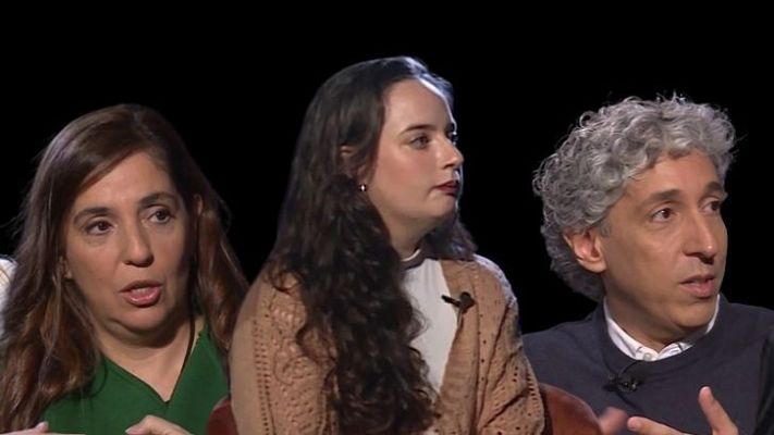 Debate televisivo con tres participantes: dos mujeres y un hombre, gesticulando activamente mientras miran fuera de cámara.  Título: \"Voces Maestras\".