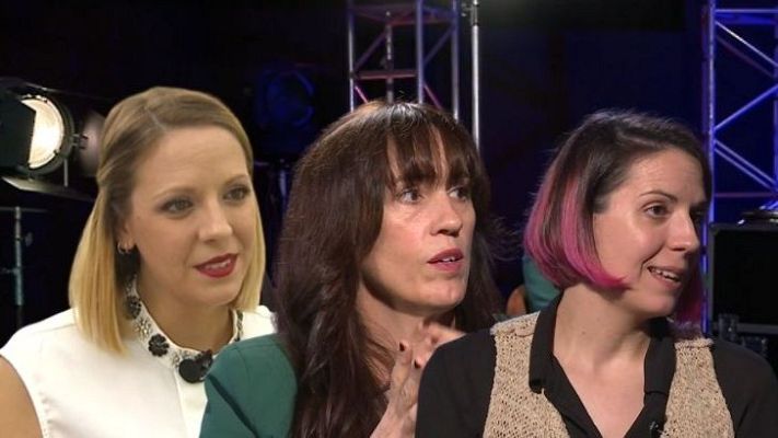 Tres mujeres con diferentes estilos de cabello y ropa discuten en un set de grabación.  Se observa texto superpuesto relacionado con la dirección de ficción.