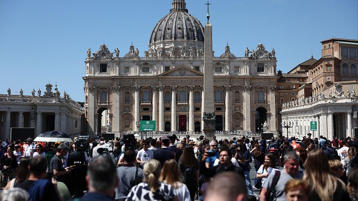 Multitud congregada ante la Basílica de San Pedro, día soleado.  Numerosos equipos de prensa presentes.  Evento de gran importancia mediática.