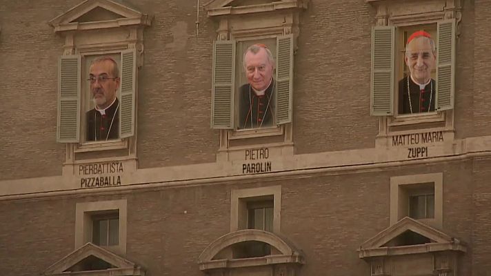 Tres retratos de cardenales en ventanas superiores de un edificio beige, con ventanas más grandes debajo.  Los nombres de los cardenales aparecen bajo sus retratos.