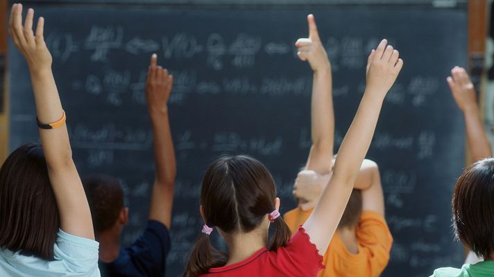 Un grupo de niños levanta las manos para intervenir en la clase