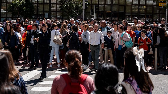 Multitud de personas cruzando una calle, con presencia policial para gestionar el flujo peatonal.  Escena urbana cotidiana.