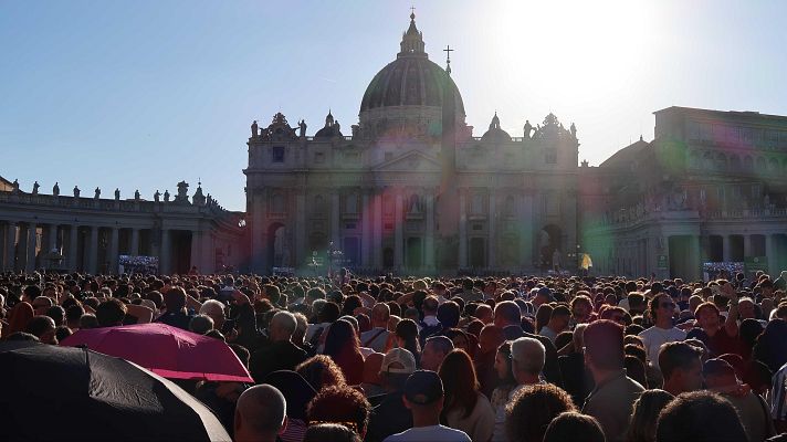 Multitud en la Plaza de San Pedro celebrando la elección papal.  La Basílica de San Pedro al fondo, ambiente festivo con paraguas.